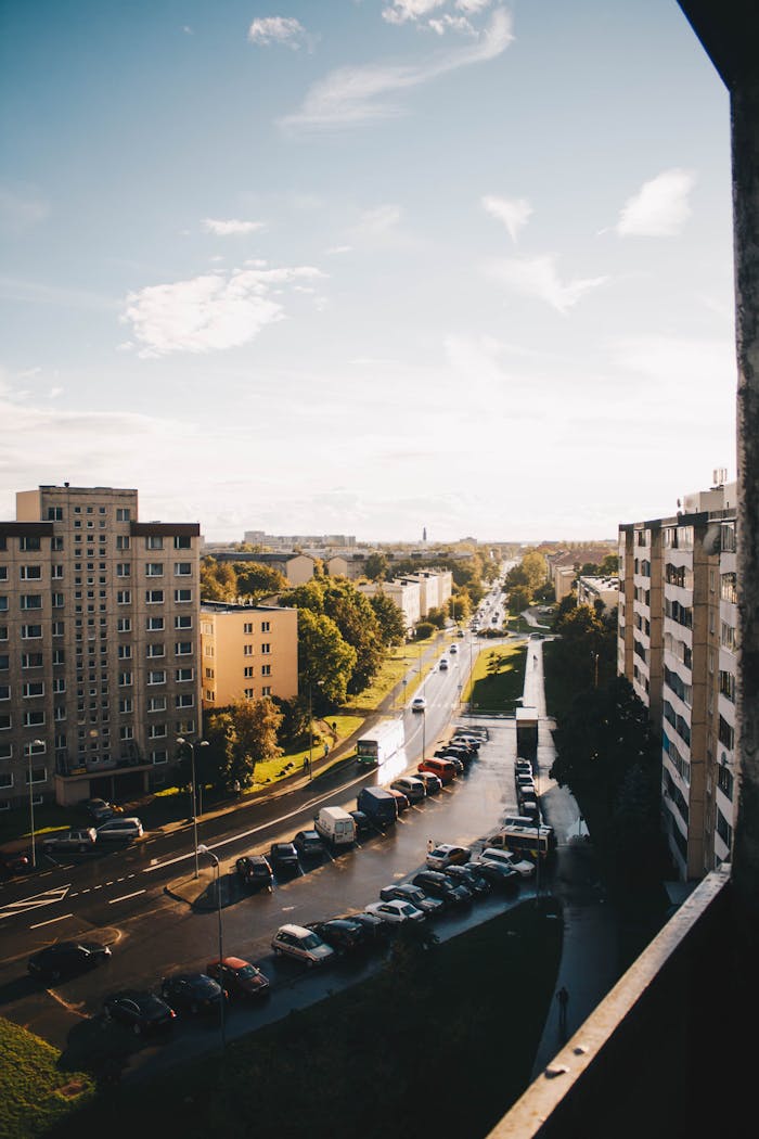 services-03 High-angle view of a urban street, featuring apartment buildings and parked cars under daylight.